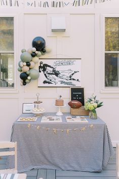 a table that has some food on it and balloons hanging from the wall behind it