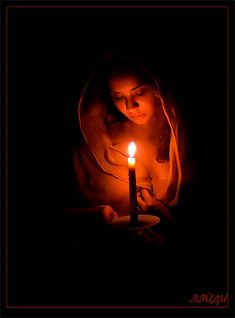 a woman holding a lit candle in her hands