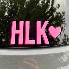 a pink sticker with the word hlk on it and a heart in the middle