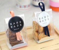 two bags of cookies sitting on top of a wooden cutting board with ribbons around them