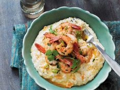 a bowl filled with rice and shrimp on top of a blue cloth next to a fork