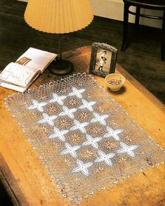 a table topped with a doily on top of a wooden table next to a lamp