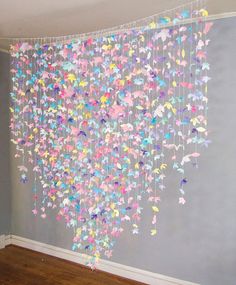 a room with a wall hanging made out of paper butterflies and streamers on the ceiling