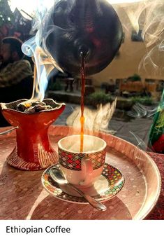 coffee being poured into a cup on top of a saucer