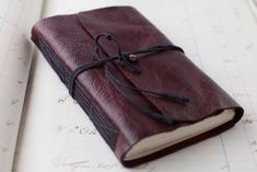 a brown leather journal tied to a white book