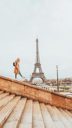 a woman walking up some steps in front of the eiffel tower