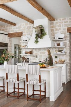 a kitchen with white walls and wooden floors has an island in front of the stove