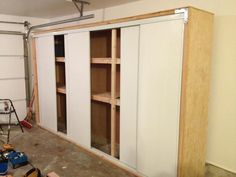 an unfinished room with shelves and tools on the floor in front of a garage door