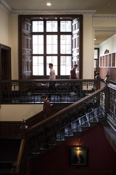 two people are walking down the stairs in an old building with wood and metal railings