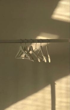 four pairs of clothes hang on a rack in the sun, with one hanging off to the side