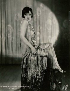 an old black and white photo of a woman sitting on a stool