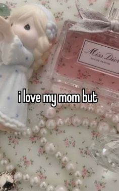 an angel figurine next to a bottle of perfume on a table with pearls