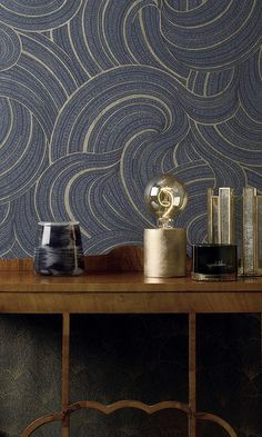 a wooden table topped with books and vases next to a wallpapered wall