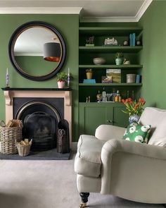 a living room filled with furniture and a fire place in front of a green wall