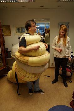 a man and woman standing next to each other in front of a giant balloon snake