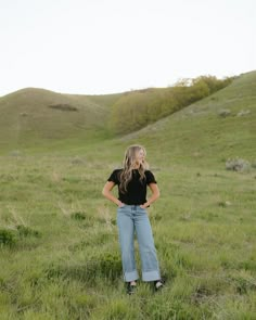 a woman standing in a field with her hands on her hips