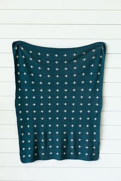 a teal blanket with white crosses on it hanging from the side of a wall