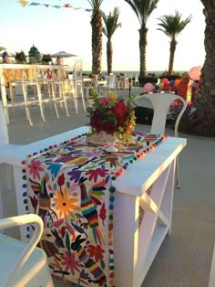 the table is decorated with colorful flowers and pom - poms for an outdoor party