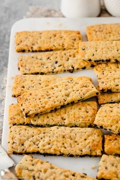 crackers are arranged on a white tray next to a cup of milk and spoons