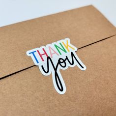 a thank you sticker sitting on top of a brown box