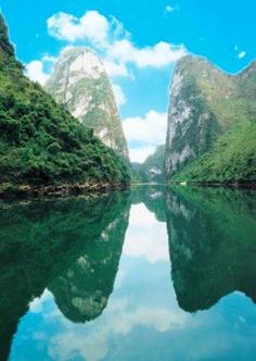 the water is calm and clear with mountains in the background