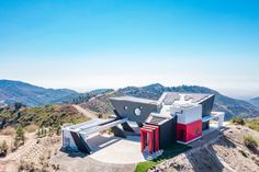 an aerial view of a house on top of a hill with mountains in the background