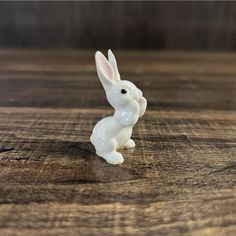 a white rabbit figurine sitting on top of a wooden table