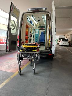 an ambulance with its doors open and medical equipment in the foreground, on wheels