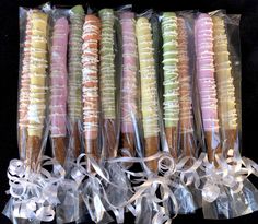 six different colored cookies wrapped in clear cellophane and tied with white ribbon on black background