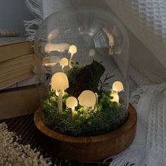 a group of mushrooms in a glass dome with moss and lit candles on a table