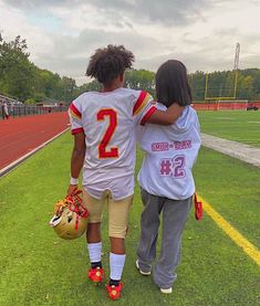 two people walking on a football field together