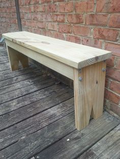 a wooden bench sitting on top of a wooden deck next to a brick wall and floor