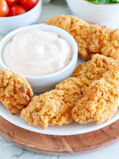 fried chicken rings on a plate with ranch dip and tomatoes in the bowl behind them