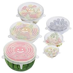 four plastic food containers with lids on each side and one containing vegetables in the middle