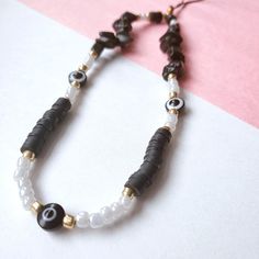 a black and white beaded necklace on a pink and white tablecloth with gold accents