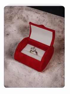 an open red velvet ring box with a diamond in it