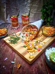 a cutting board topped with lots of food next to two bowls filled with different foods