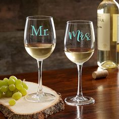 two wine glasses with the word mr and mrs on them sitting next to some grapes