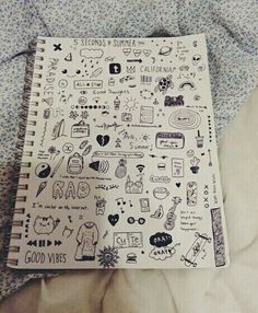 a notebook covered in doodles on top of a bed