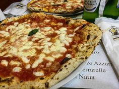 two large pizzas sitting on top of a table next to bottles of water and napkins