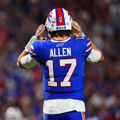 a football player is holding his hands up to his head as he stands on the field
