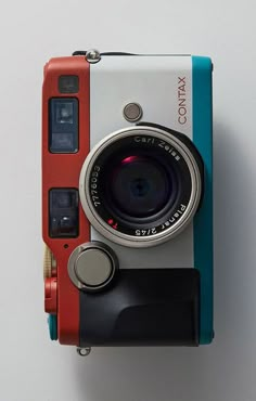 an old camera sitting on top of a white table next to a blue and red case