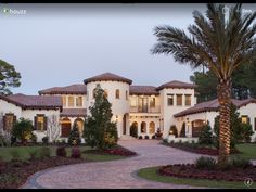 a large white house with palm trees in the front yard and walkway leading to it