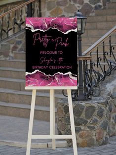 a welcome sign for a birthday celebration with pink flowers on black and white background, stands in front of stone steps