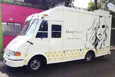 a woman's hair salon truck parked on the street in front of a pink building