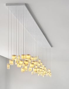 a modern chandelier hanging from the ceiling in a room with white walls and flooring