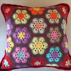 a colorful crocheted pillow on a white wall