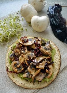 a tortilla with mushrooms and other vegetables on it sitting next to some garlic