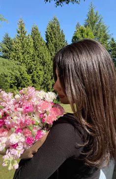 a woman sitting on a bench with flowers in her lap and looking at the sky