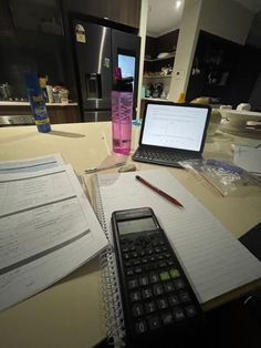 a laptop computer sitting on top of a kitchen counter next to a calculator